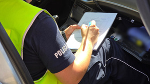 zdjęcie przedstawia policjanta sporządzającego dokumentację