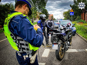 zdjęcie przedstawia policjanta kontrolującego motocykl