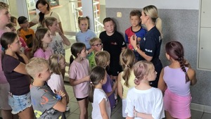 zdjęcie przedstawia policjantkę rozmawiającą z dziećmi w budynku komendy