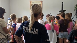 zdjęcie przedstawia policjantkę a w tle dzieci w pokoju technika kryminalistyki