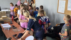 zdjęcie przedstawia policjantkę pokazującą dzieciom sprzęt policyjny