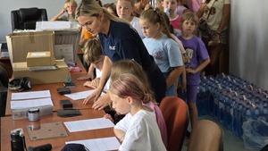 zdjęcie przedstawia policjantkę pokazującą dzieciom sprzęt policyjny