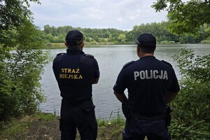 zdjęcie przedstawia strażnika miejskiego i policjanta na tle stawu