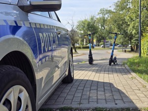 zdjęcie przedstawia radiowóz a w tle hulajnogi