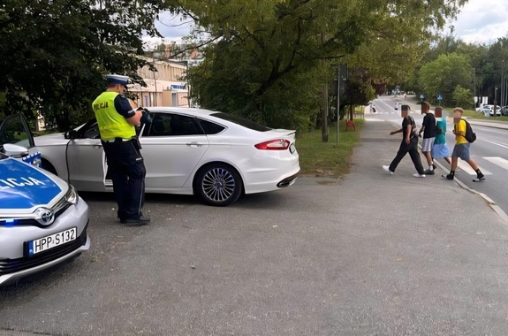 zdjęcie przedstawia policjanta kontrolującego pojazd