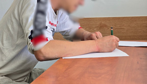 zdjęcie przedstawia zatrzymanego mężczyznę podpisującego dokumenty
