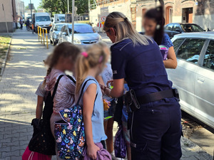 zdjęcie przedstawia policjantkę rozdającą uczniom opaski odblaskowe