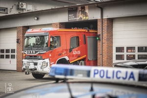 zdjęcie przedstawia belkę radiowozu policyjnego a w tle wóz strażacki