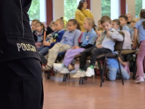 zdjęcie przedstawia zbliżenie na napis na spodniach policja a w tle dzieci
